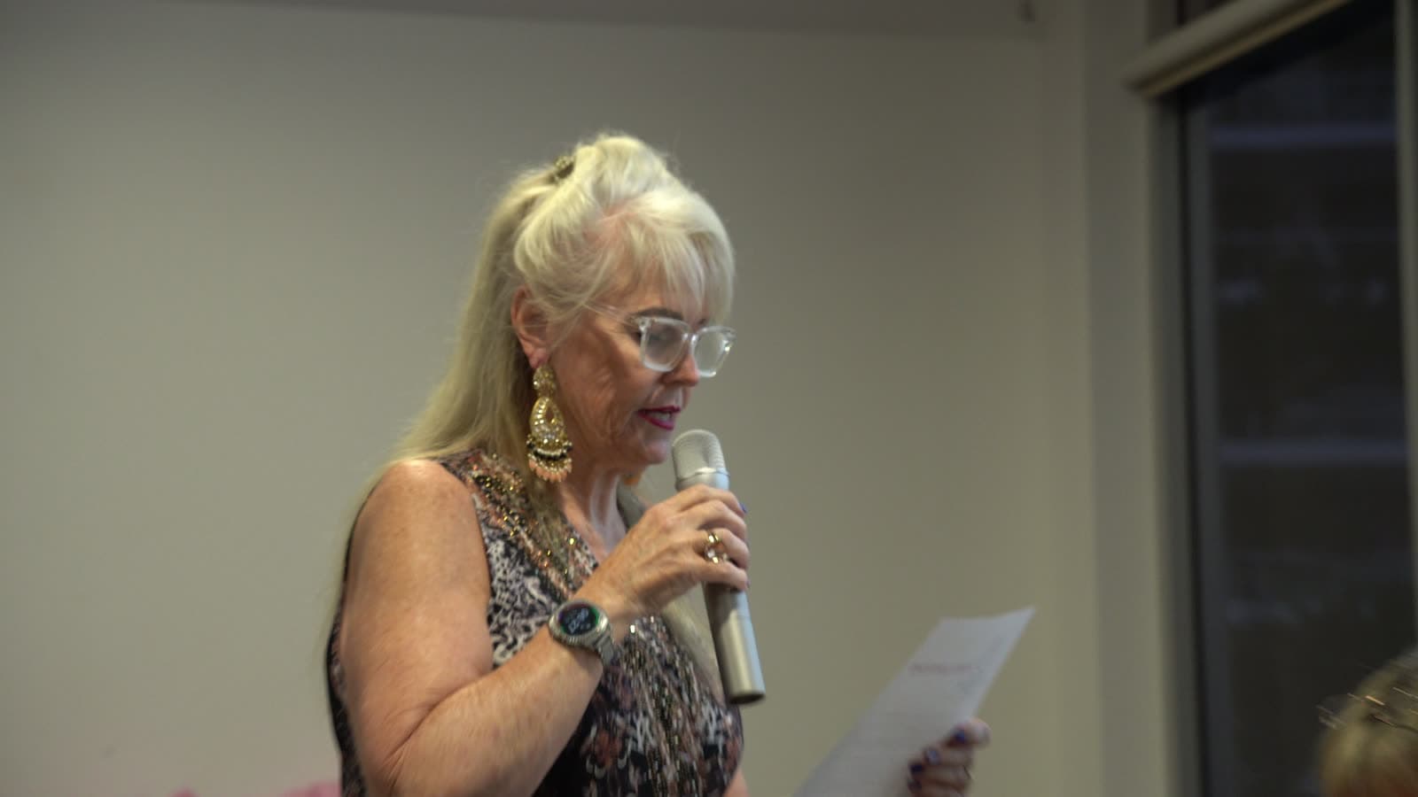 Marion Simon speaking to the room with a microphone during the welcome.